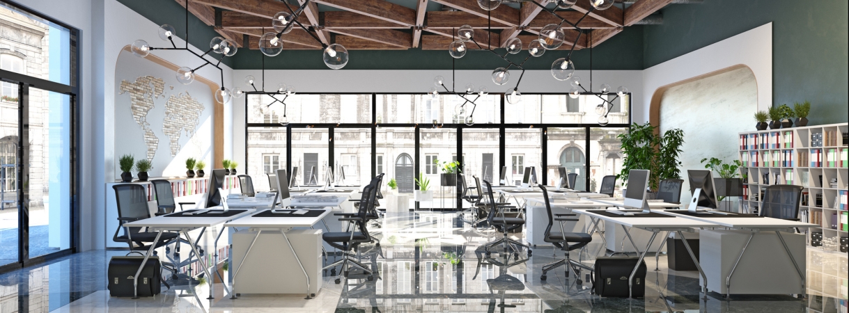 Modern office with a mix of remote and in-person employees collaborating via video screens and shared workspaces.